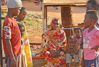 Bildunterschrift: Eine junge Mutter mit ihren Kindern und weiteren Kindern in einem Lager für Binnenvertriebene in Sennar, Sudan (Copyright: Islamic Relief).