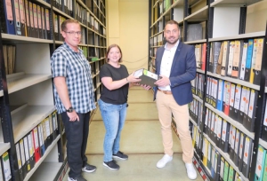 Registrator Daniel Herberich (l.) und der Leiter des Fachbereichs Zentrale Dienste und Vergabestelle André Feil (r.), übergeben Sabrina Greß (2.v.l.) von der Lebenshilfe Schweinfurt symbolisch den ersten Aktenordner. In den kommenden Monaten werden weitere Hunderte zur Aufarbeitung und Digitalisierung folgen. Foto: Tim Großmüller