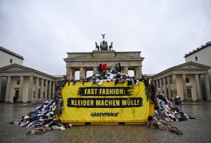 Çevreci örgüt Greenpeace, tekstil atıklarına dikkat çekmek için Almanya&#039;nın başkenti Berlin&#039;deki Brandenburg Kapısı&#039;nda eylem yaptı. Tekstil atıklarını Brandenburg kapısının önüne döken eylemciler, oluşturdukları kıyafet kulesinin üzerine çıkarak protesto gerçekleştirdi. Foto: AA