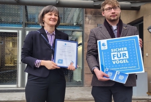 Dr. Peter Stimmler, LBV-Projektmanager des Projekts &quot;Unsichtbares sichtbar machen - Reduzierung von Vogelschlag an Glas&quot; überreicht Britta Walthelm, Referentin für Umwelt und Gesundheit, stellvertretend für das Umweltamt die Plakette &quot;Vogelfreundliche Glasfläche&quot;.  Bildnachweis: (Nicola A. Mögel / Stadt Nürnberg)